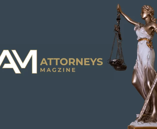 A bronze and white Lady Justice statue holding scales and a sword next to the Attorneys Magazine logo on a dark blue background.
