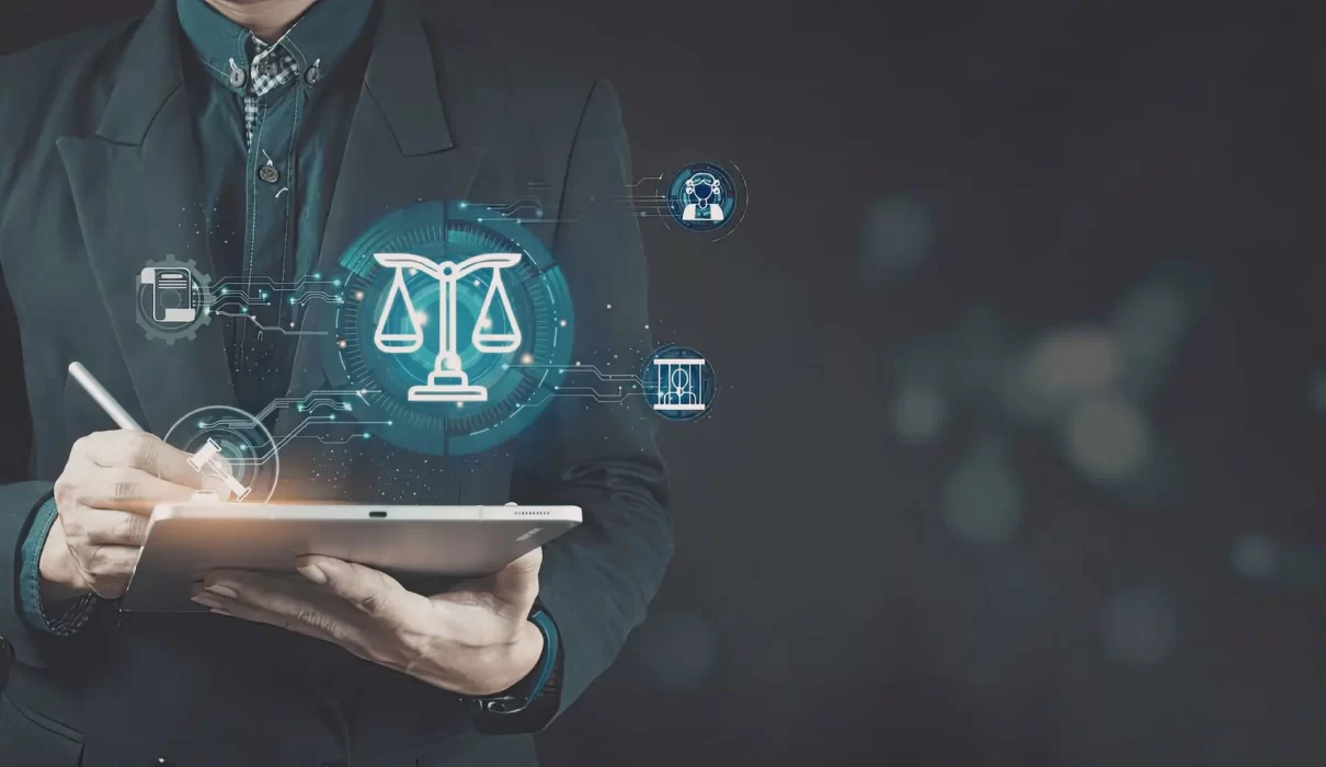 A person in a suit using a stylus on a tablet that displays glowing holographic legal icons, including the scales of justice and a gavel.