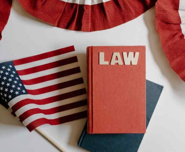 A red book labeled "LAW" sitting on a desk next to a small American flag and patriotic red, white, and blue bunting.