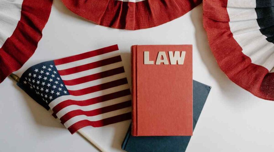 A red book labeled "LAW" sitting on a desk next to a small American flag and patriotic red, white, and blue bunting.