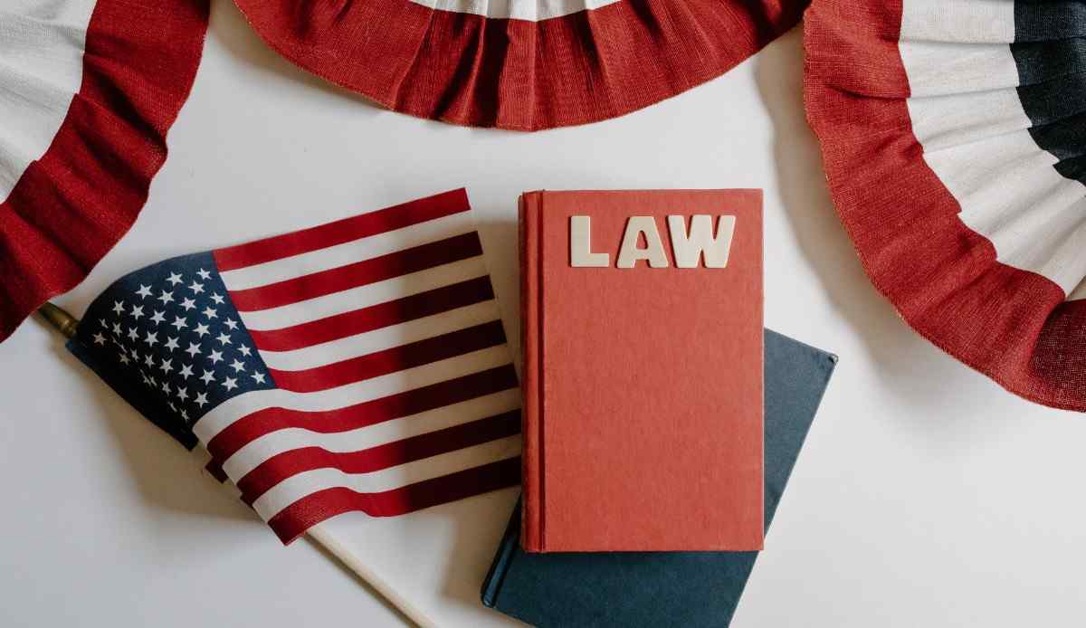 A red book labeled "LAW" sitting on a desk next to a small American flag and patriotic red, white, and blue bunting.