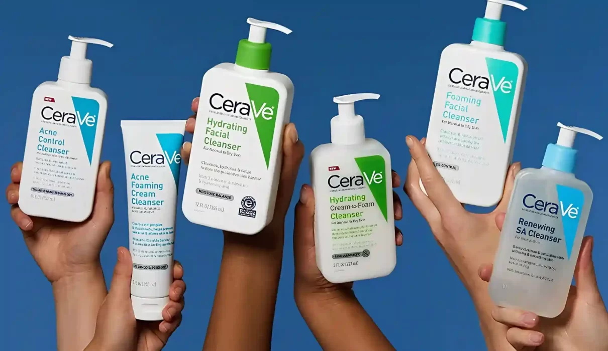 Five diverse hands hold up various white and clear plastic bottles of CeraVe skincare cleansers, including Acne Control, Hydrating Facial, Hydrating Cream-to-Foam, Foaming Facial, and Renewing SA cleansers, against a solid blue backdrop and the image is being use for CeraVe Class Action Lawsuit.